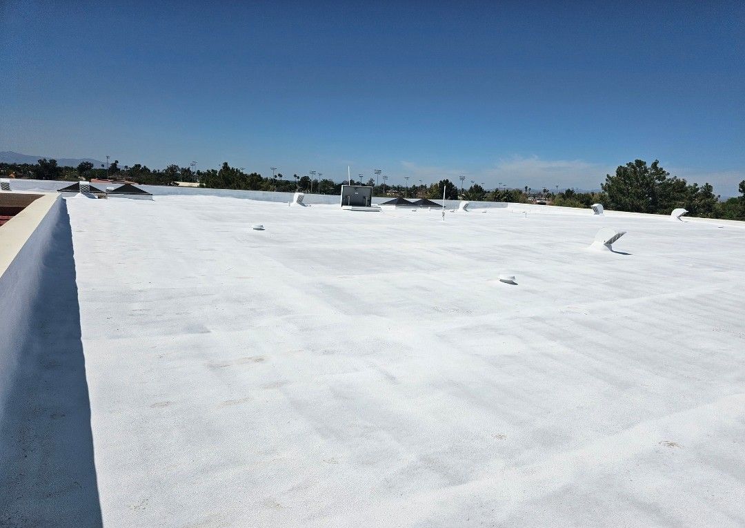 White commercial roof under a blue sky, some features visible.