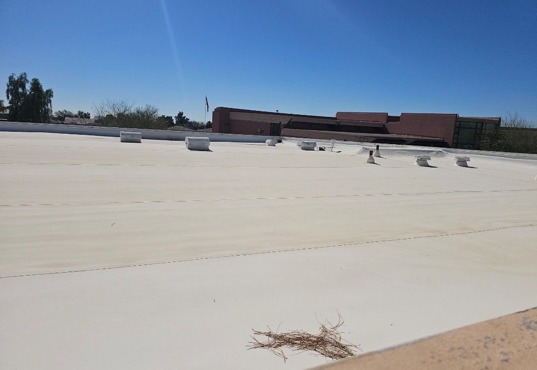 A flat, white roof on a building under a clear blue sky. White cylinders are scattered.