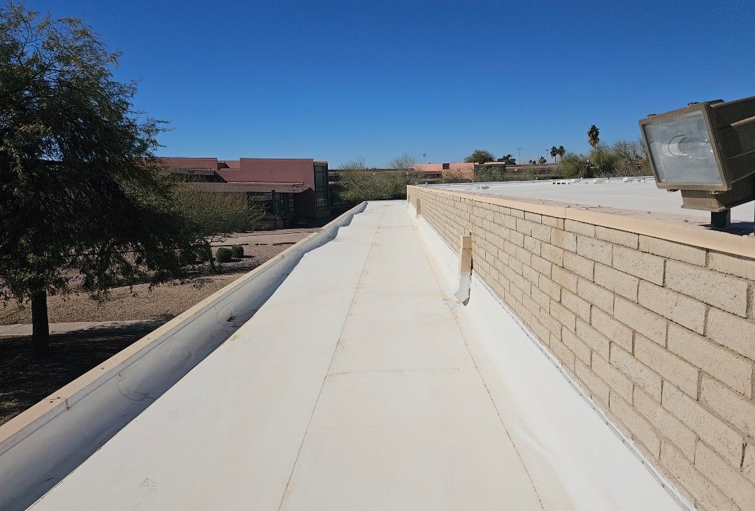 Flat white roof with brick wall on the right. Clear blue sky.