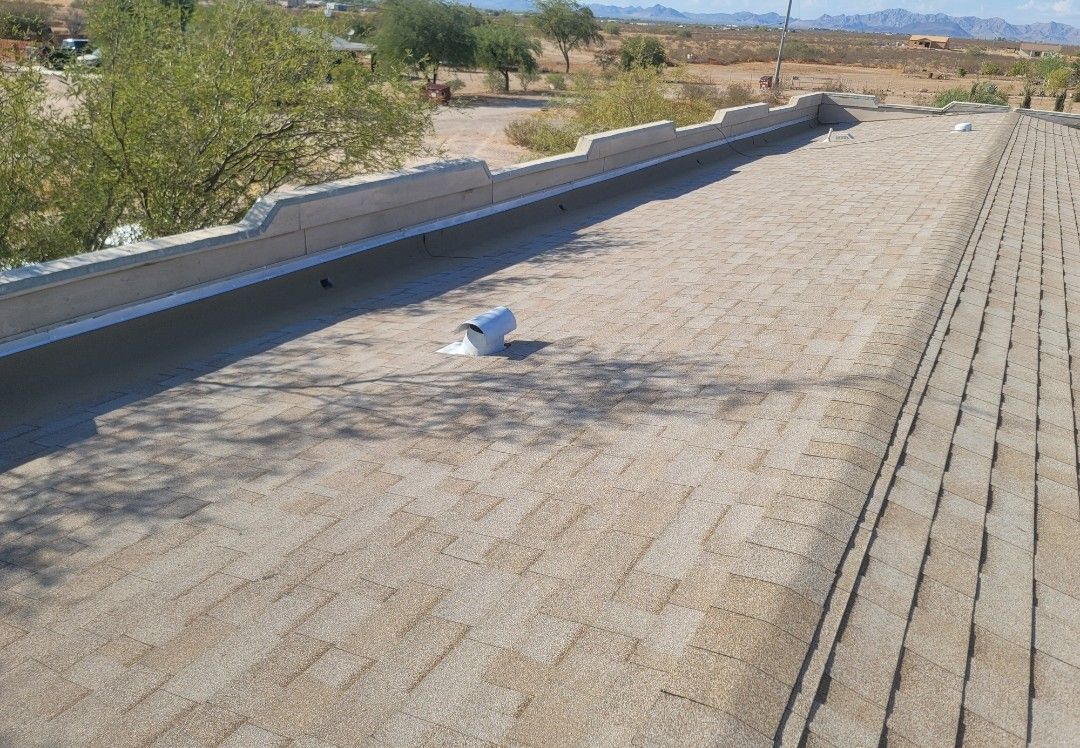 View of a light-colored, sandy-textured flat roof with a built-in gutter and a vent.