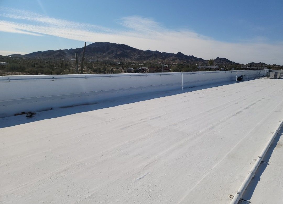 White roof with a mountain in the background under a blue sky.