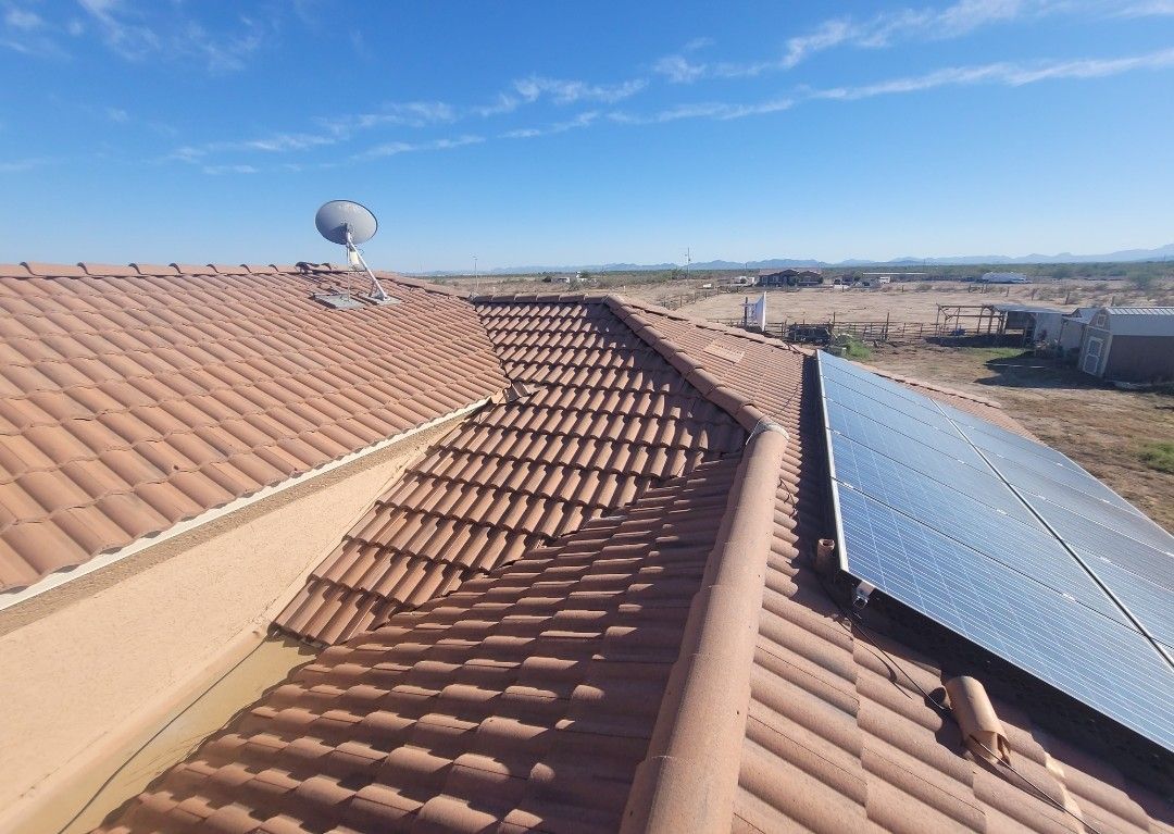 Red tile roof with solar panels, satellite dish, and open sky.
