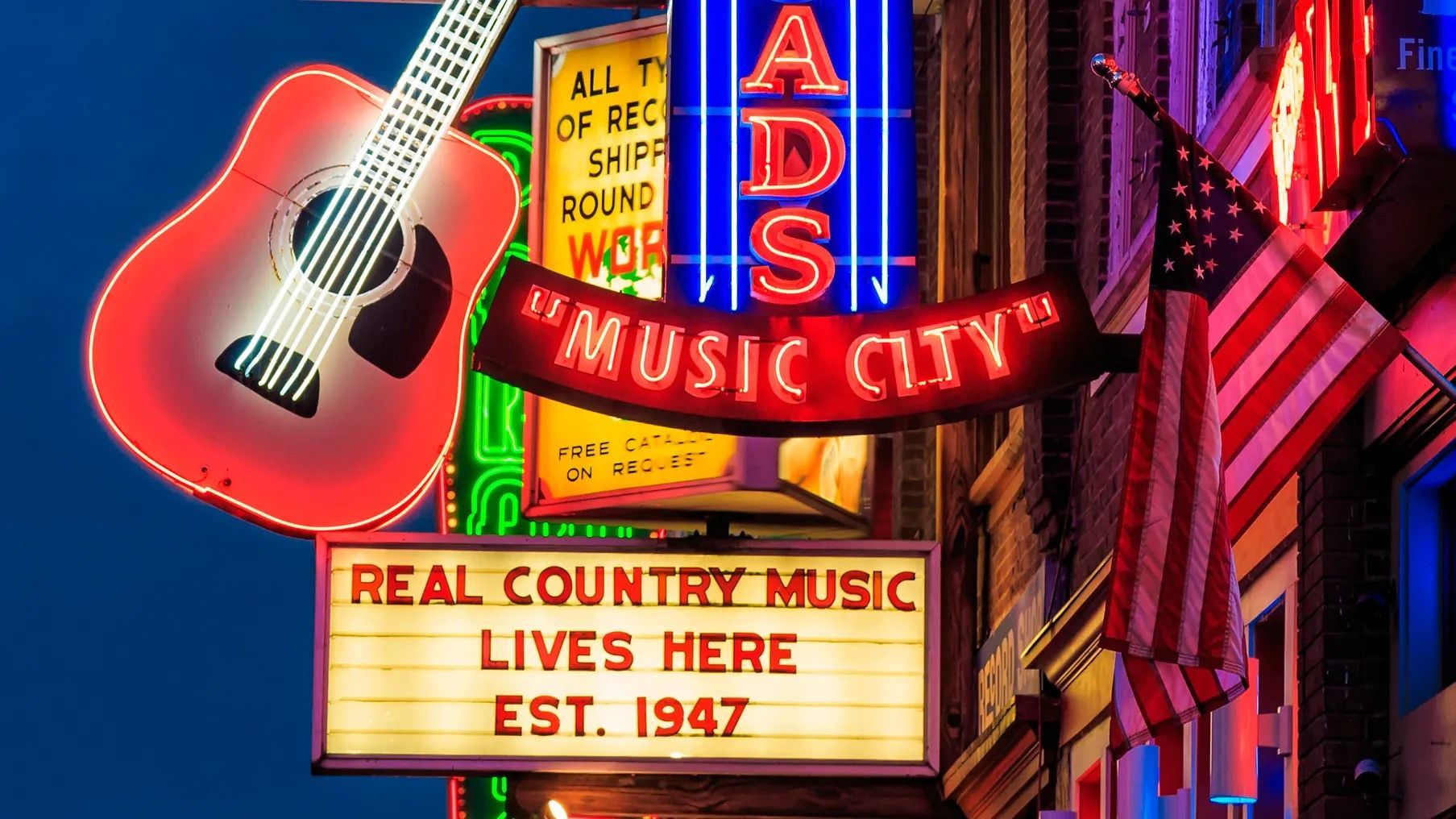 Nashville neon sign with guitars and a marquee reading “Real Country Music Lives Here Est. 1947.”