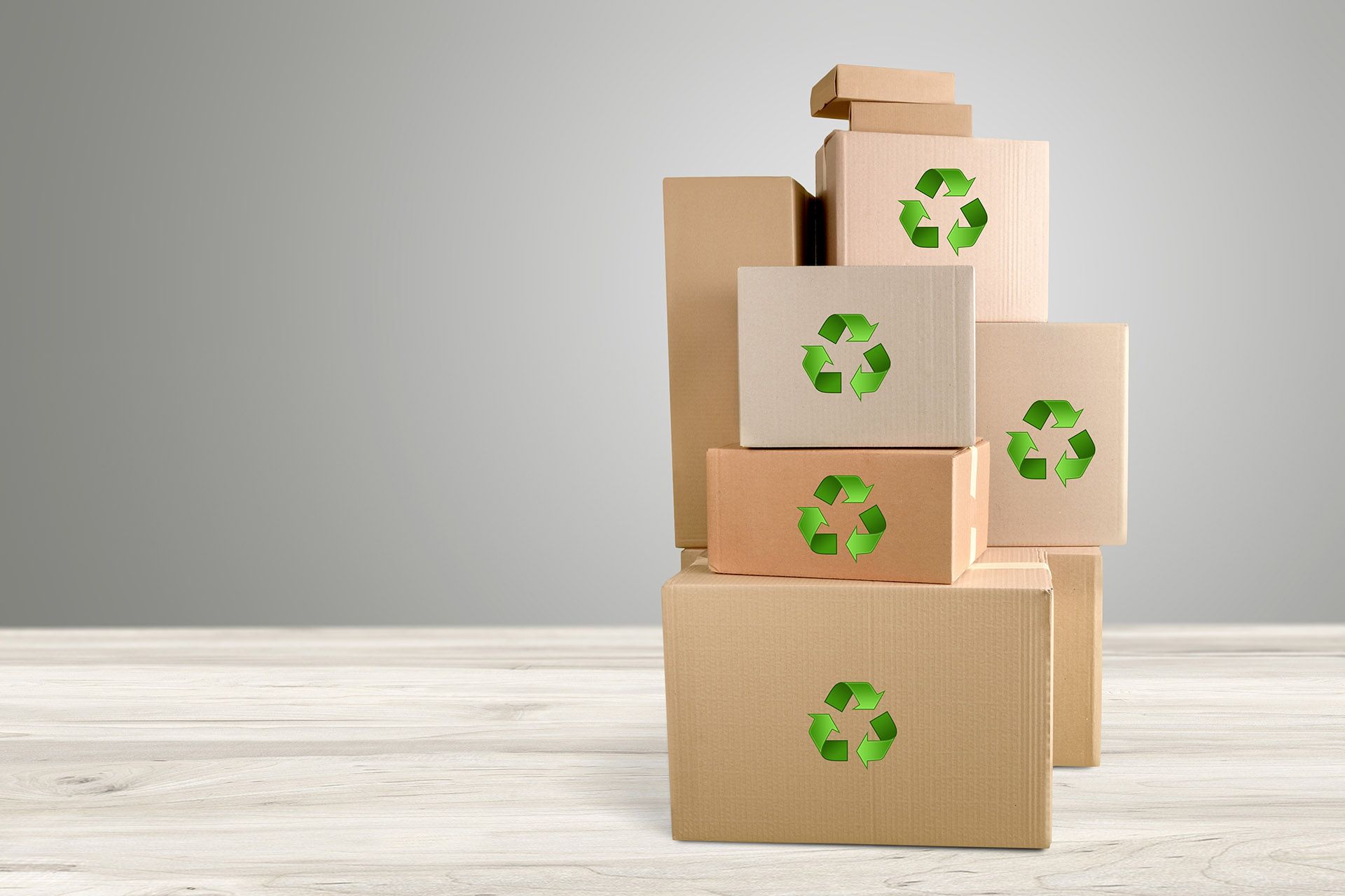 Cardboard boxes stacked with green recycling symbols.