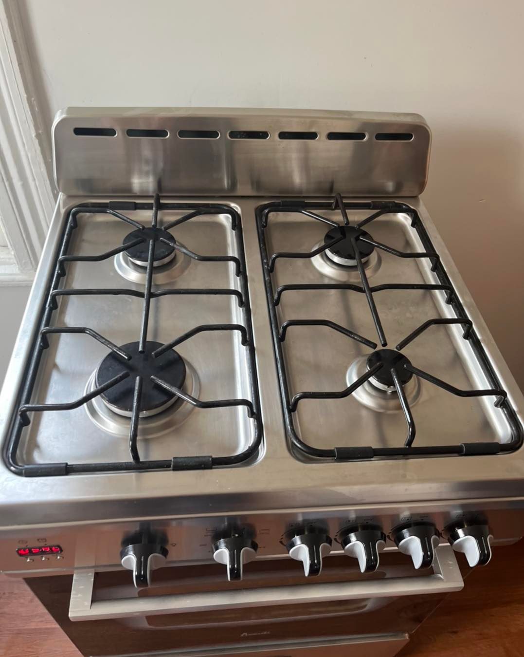 Stainless steel gas stove with four burners, black grates, and control knobs.