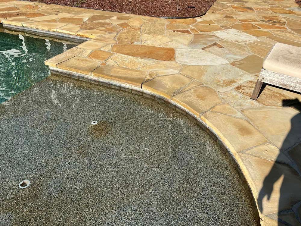 Poolside with flagstone coping and decking; water reflecting light.