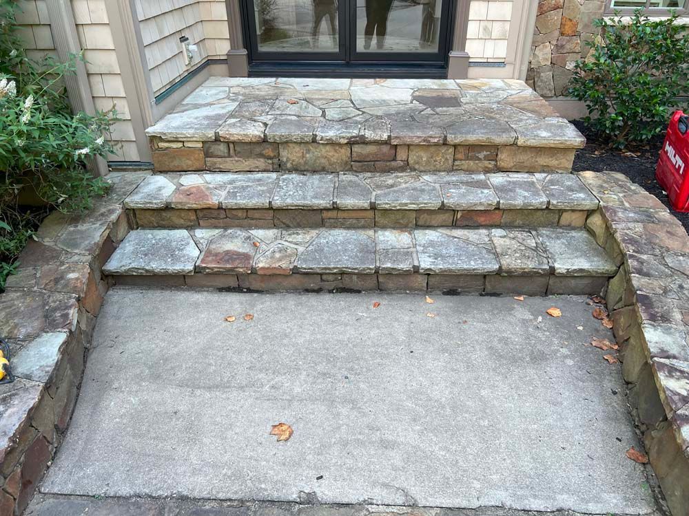 Stone steps leading to a doorway, with a concrete landing.
