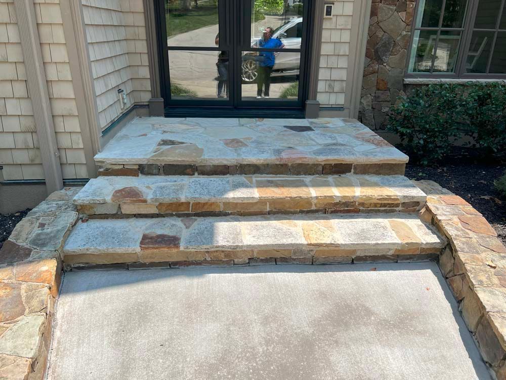 Stone steps leading to a front door with glass panels.