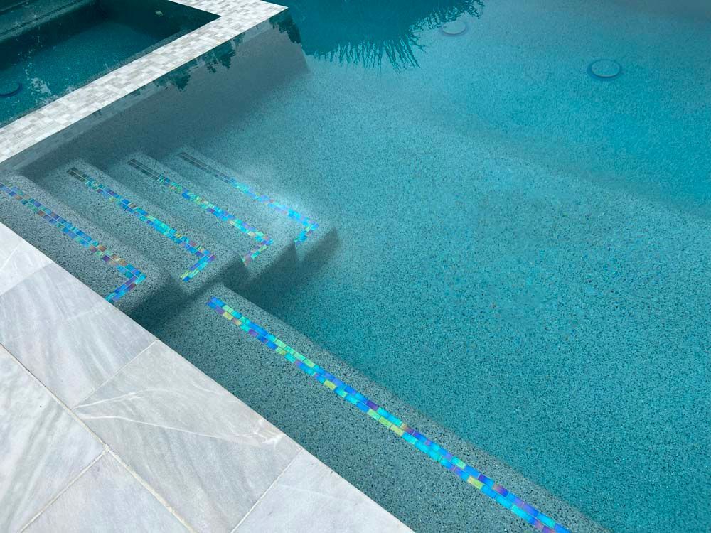 Pool with in-water steps, iridescent tile details, and turquoise water.