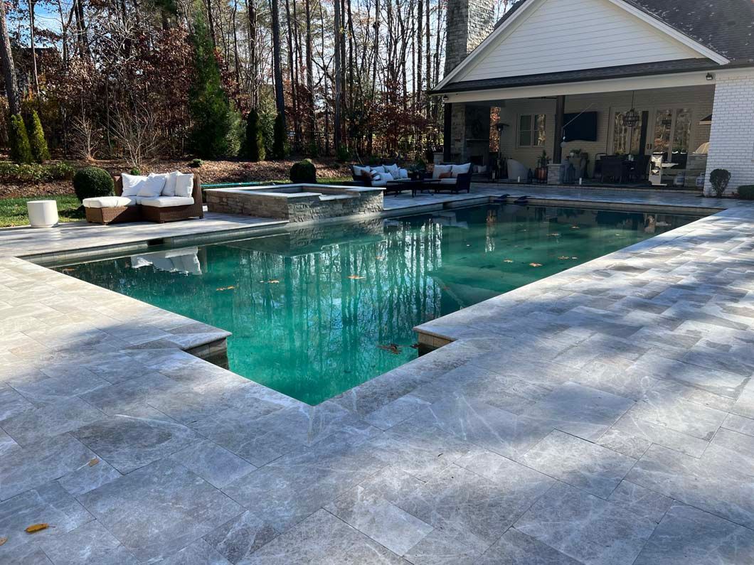 There is a large swimming pool in the backyard of a house.