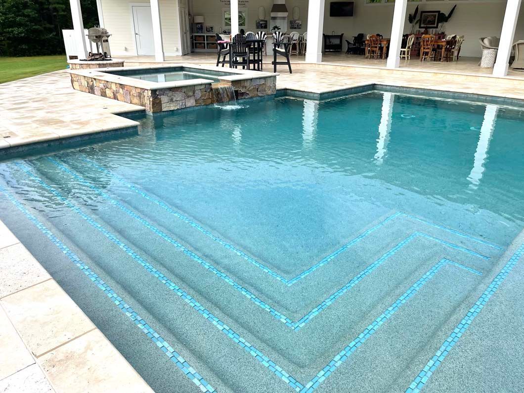 A large swimming pool with stairs leading to it in a backyard.