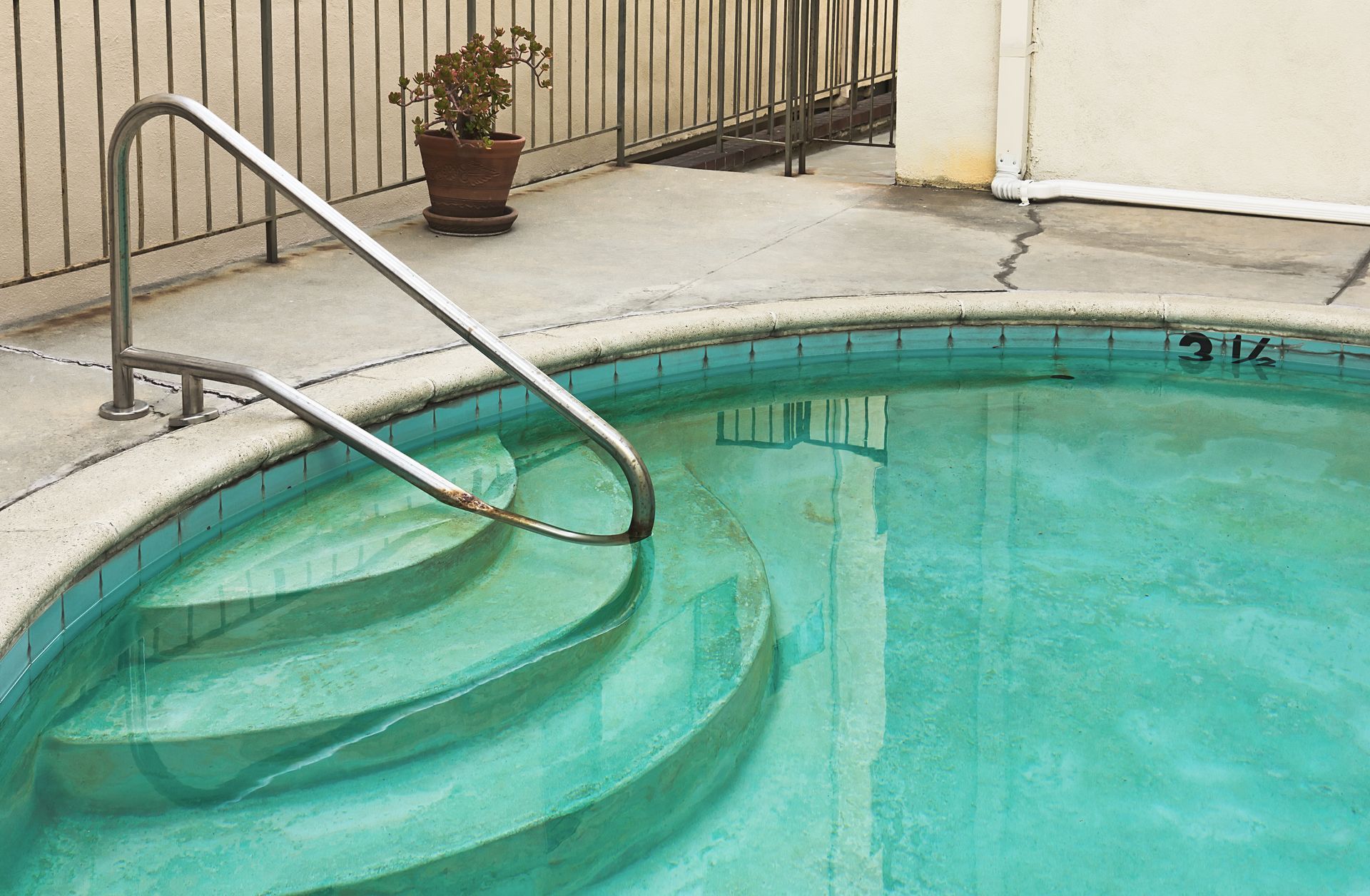 Circular pool with steps and a metal railing.
