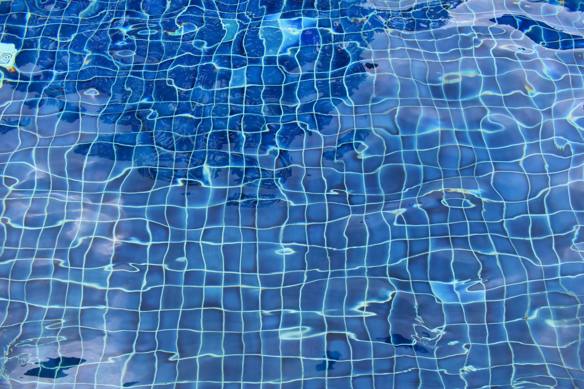 Blue pool water with tiled surface reflecting light and movement.