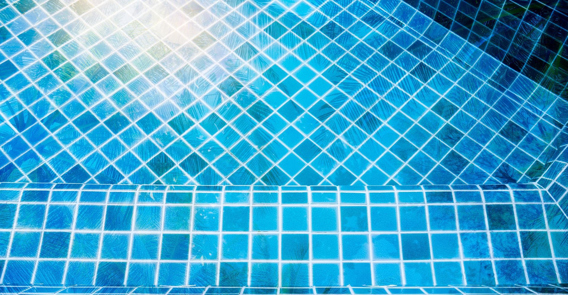 Blue tiled pool, water reflecting sunlight. Steps lead into the pool.