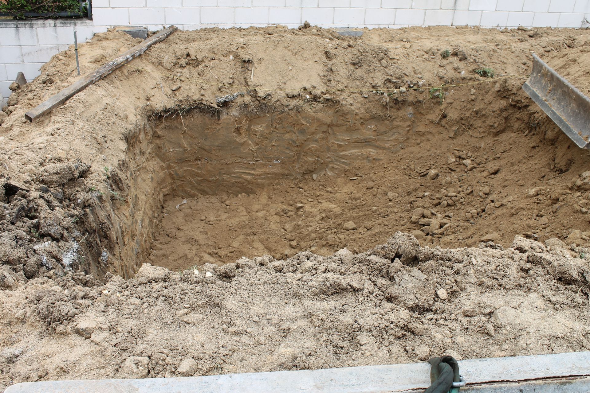 Excavated rectangular pit in the ground, surrounded by loose soil.