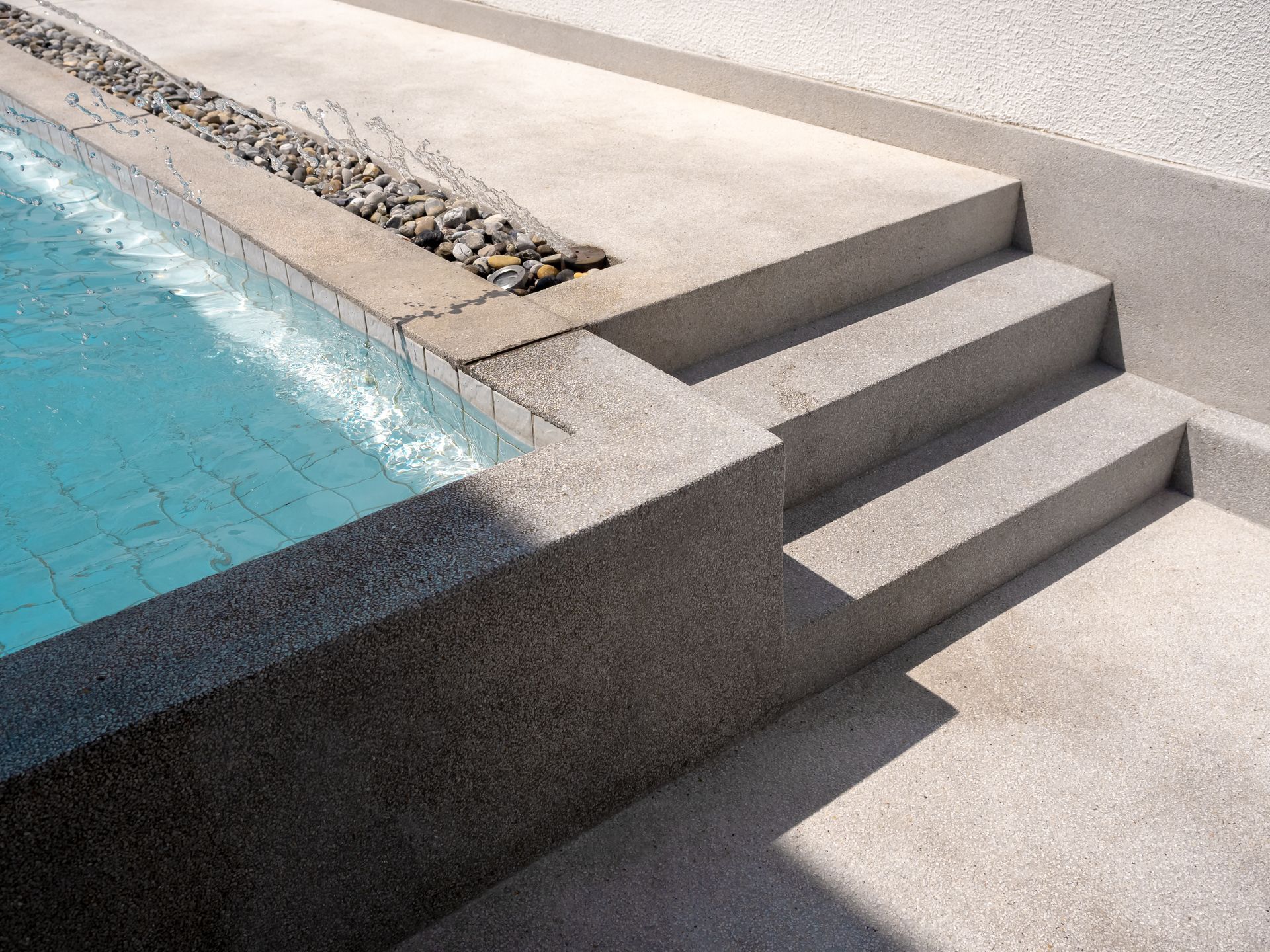 Swimming pool with gray concrete steps and edge. Blue water.