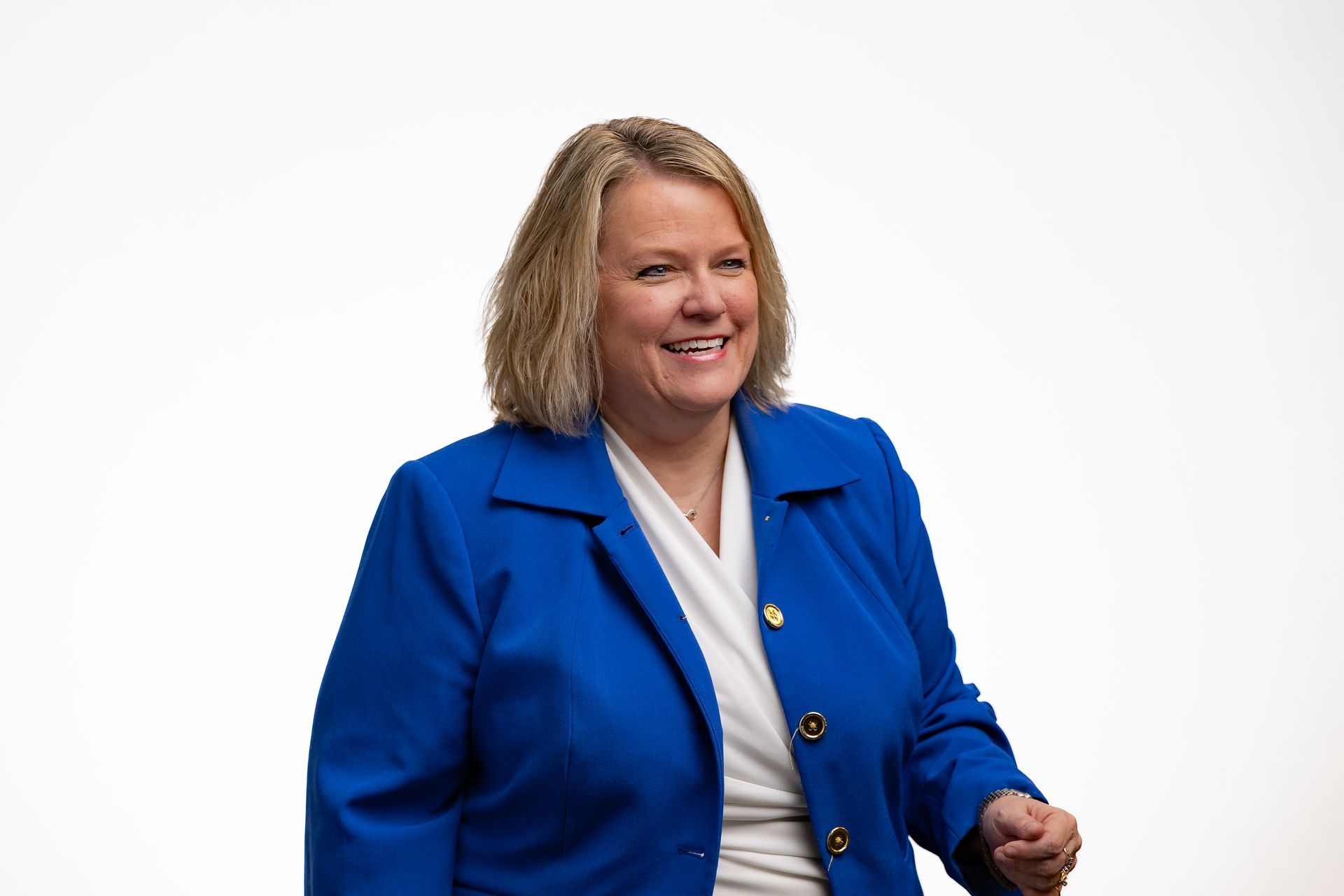 Dr. Celina in a blue blazer smiles, standing against a white background.