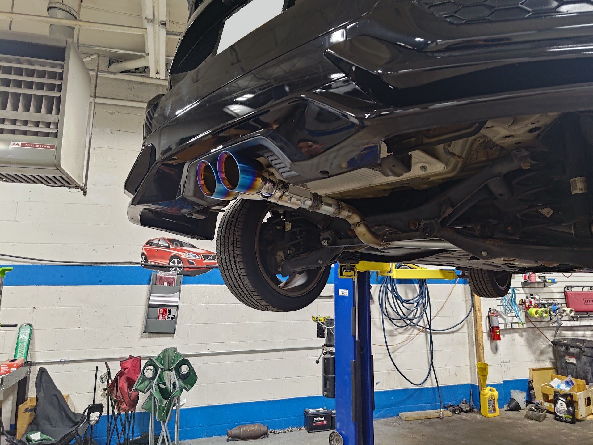 Black car on a lift, rear underside visible | La Saga Auto