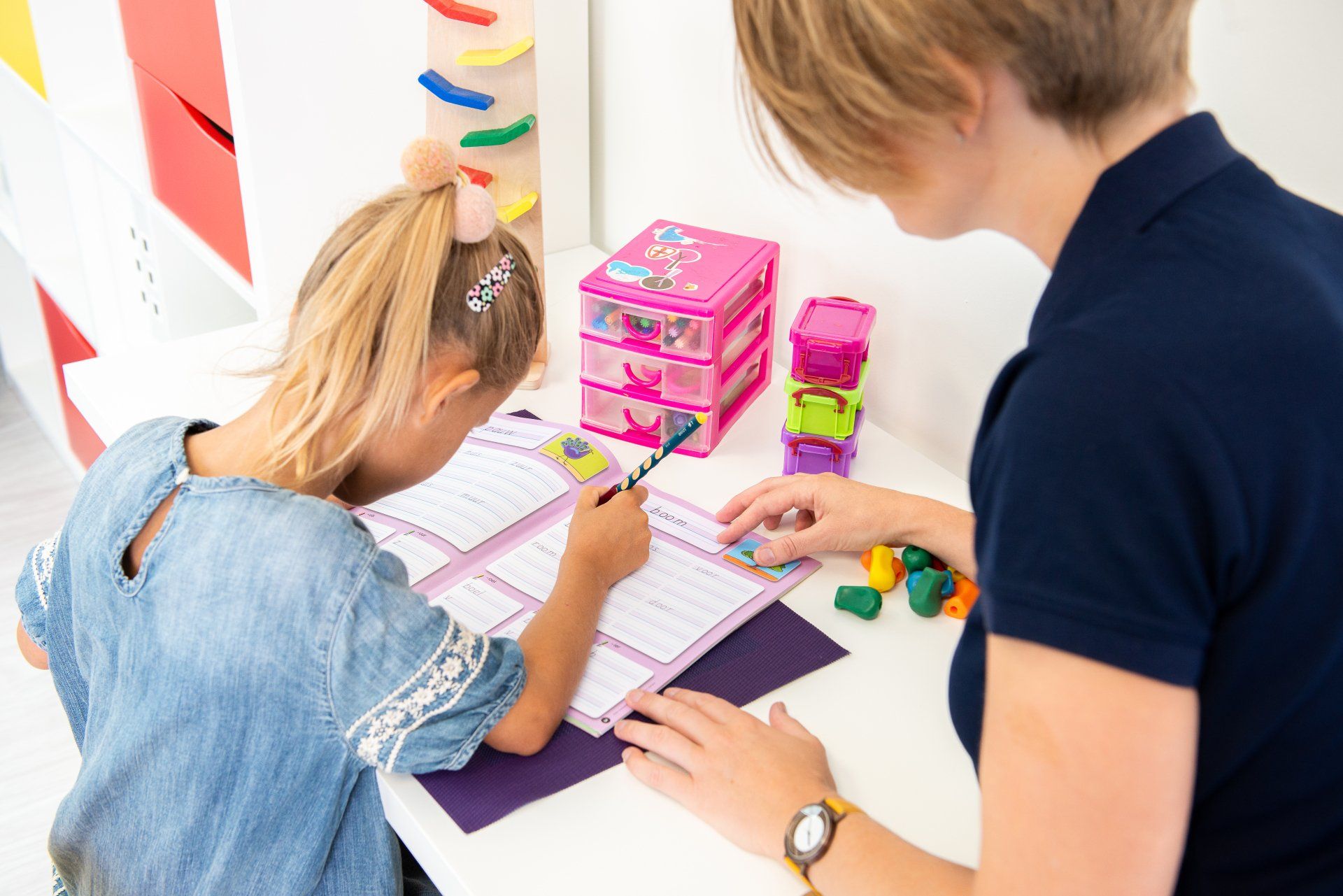 Een vrouw helpt een klein meisje met haar huiswerk.