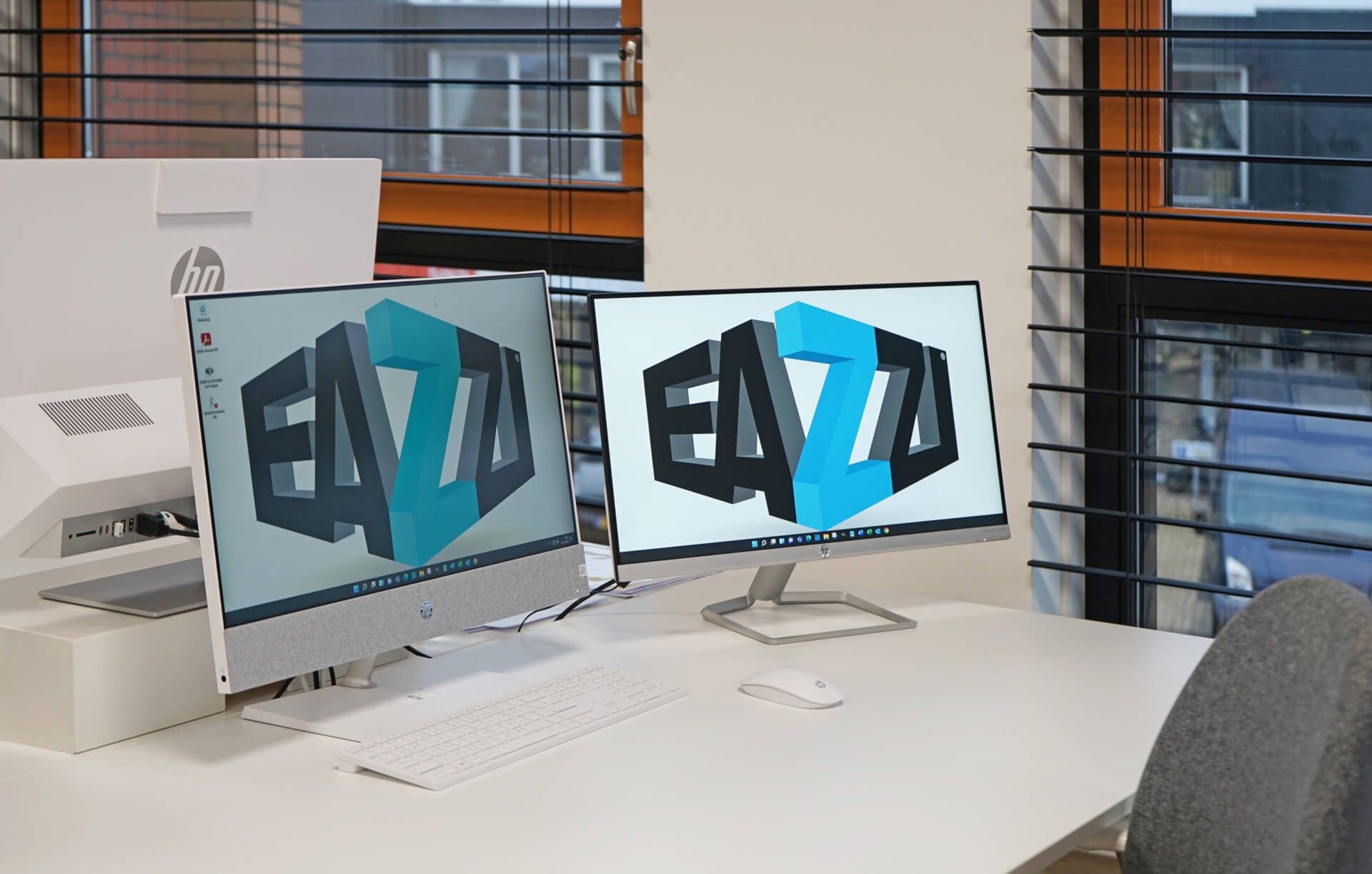 Twee computermonitoren met de letters EAZZI erop