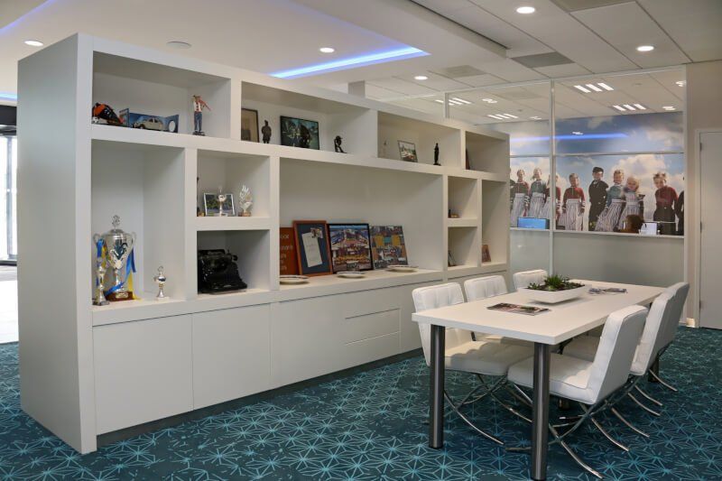 Een eetkamer met een tafel, stoelen en planken.