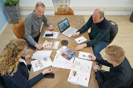 Het team van EAZZI zit met laptops rond een tafel.