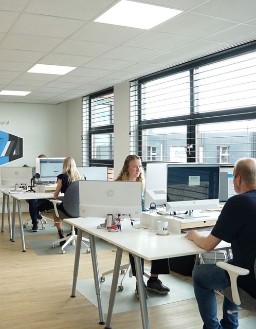 Het team van EAZZI zit rond een tafel met laptops en papieren.