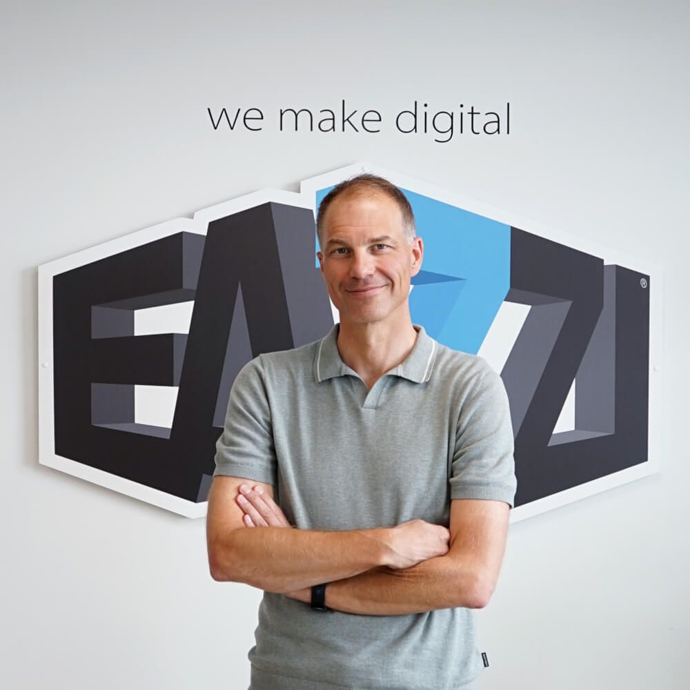 Erwin staat voor het logo van EAZZI met slogan We make digital