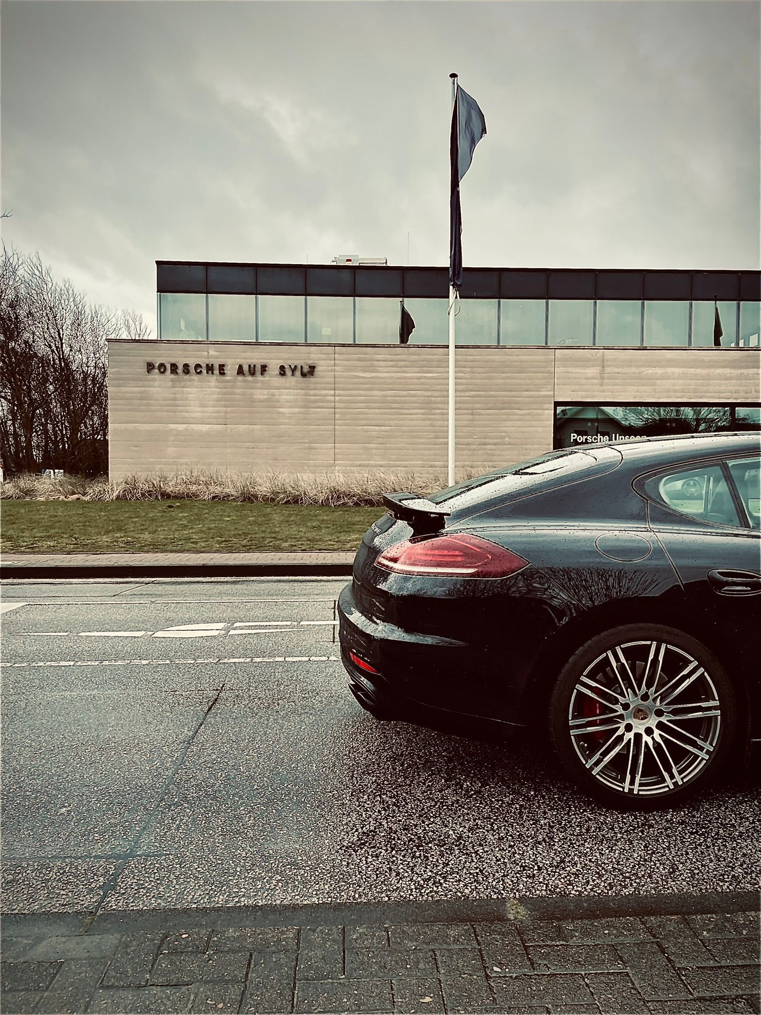 Ein schwarzes Auto parkt am Straßenrand vor einem Gebäude.