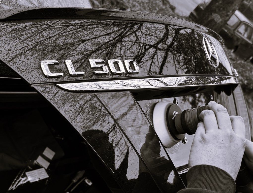 Ein Schwarzweißfoto einer Person, die einen Mercedes CL 500 poliert