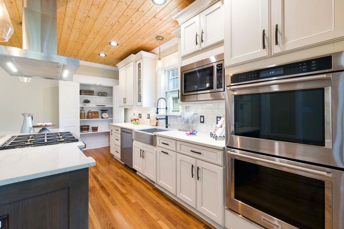 Remodeled kitchen with white cabinets, wood floor and stainless steel appliances