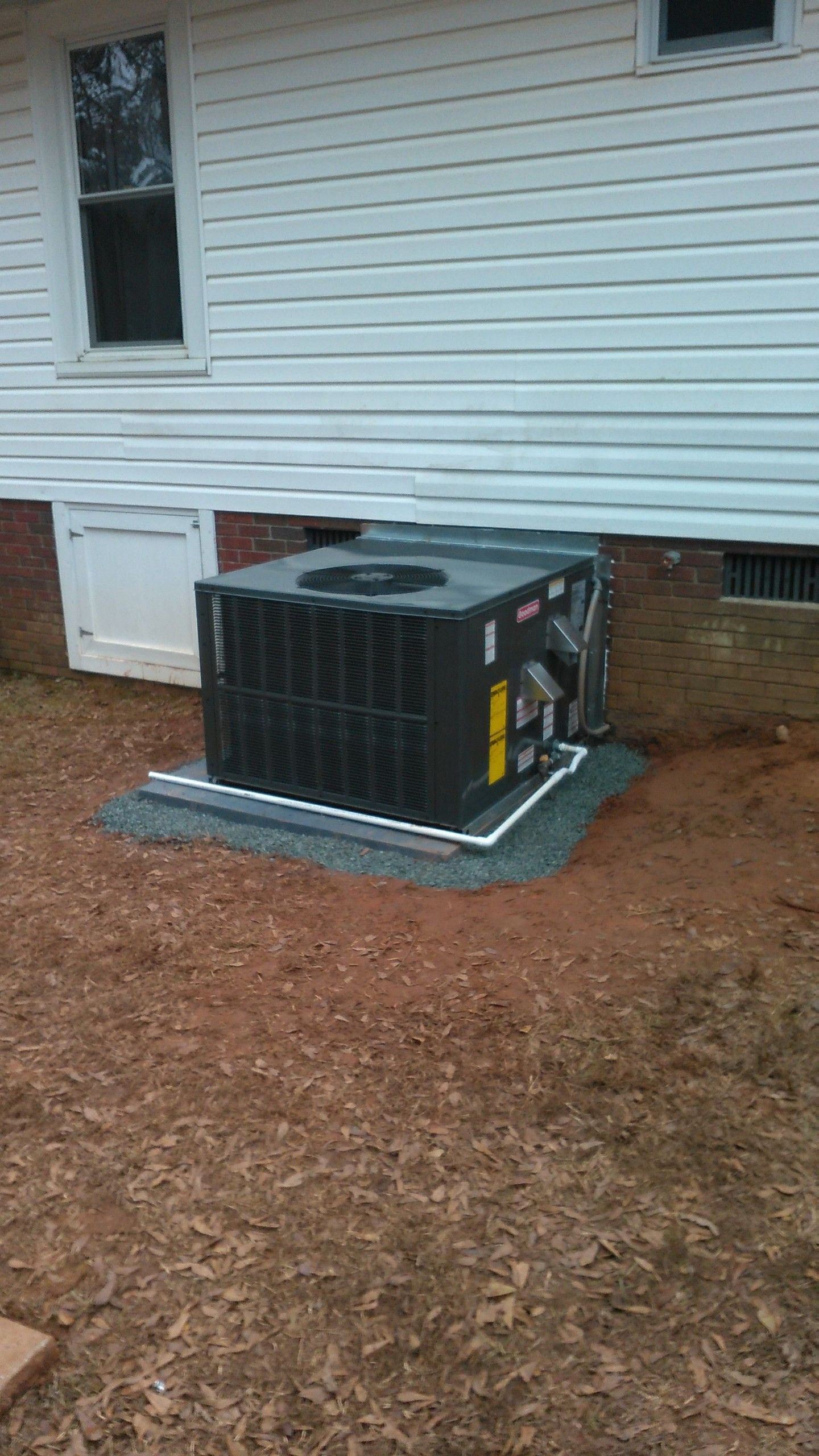 An air conditioner is sitting on the side of a house.