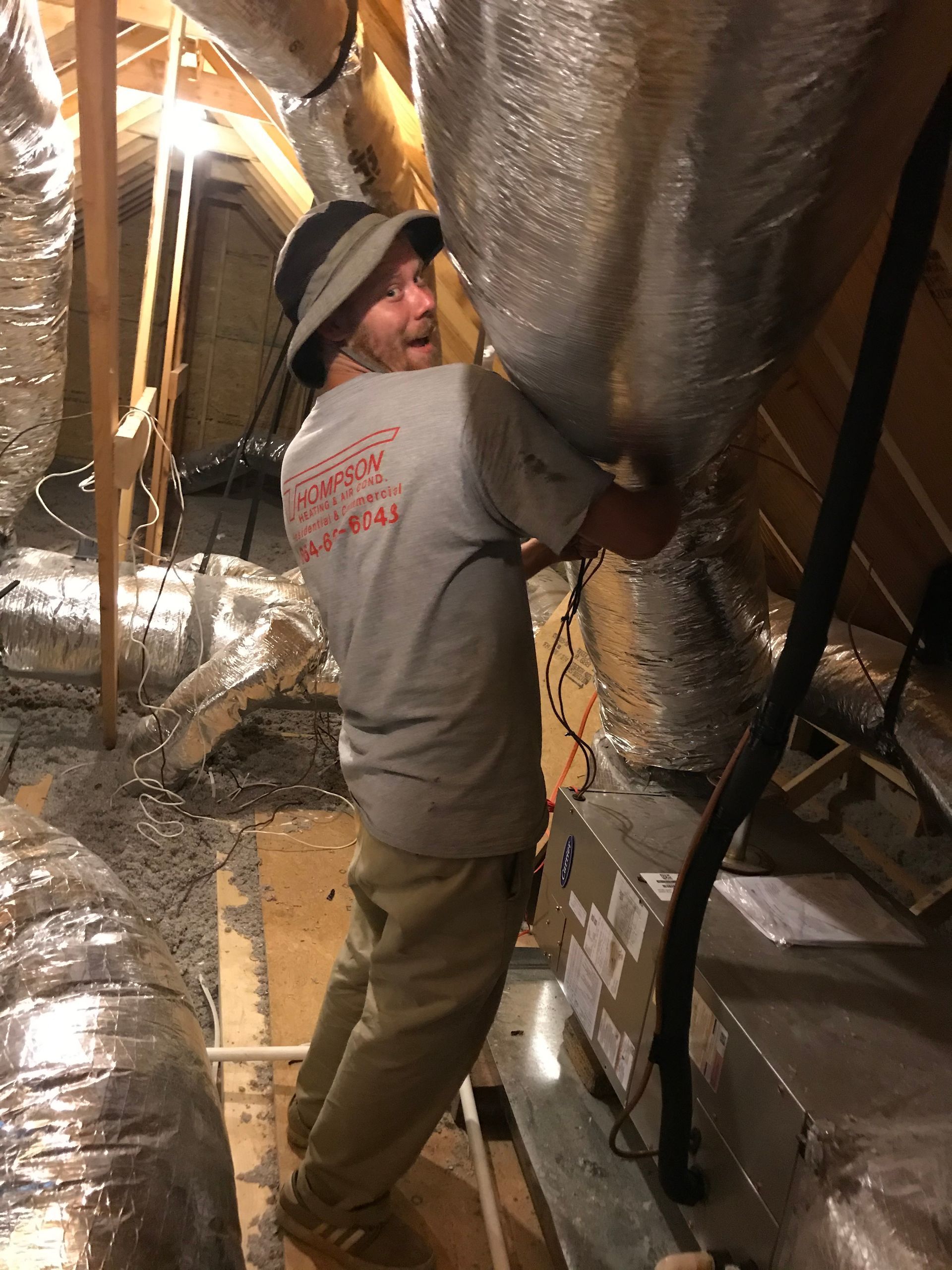 A man wearing a hat is working in an attic.