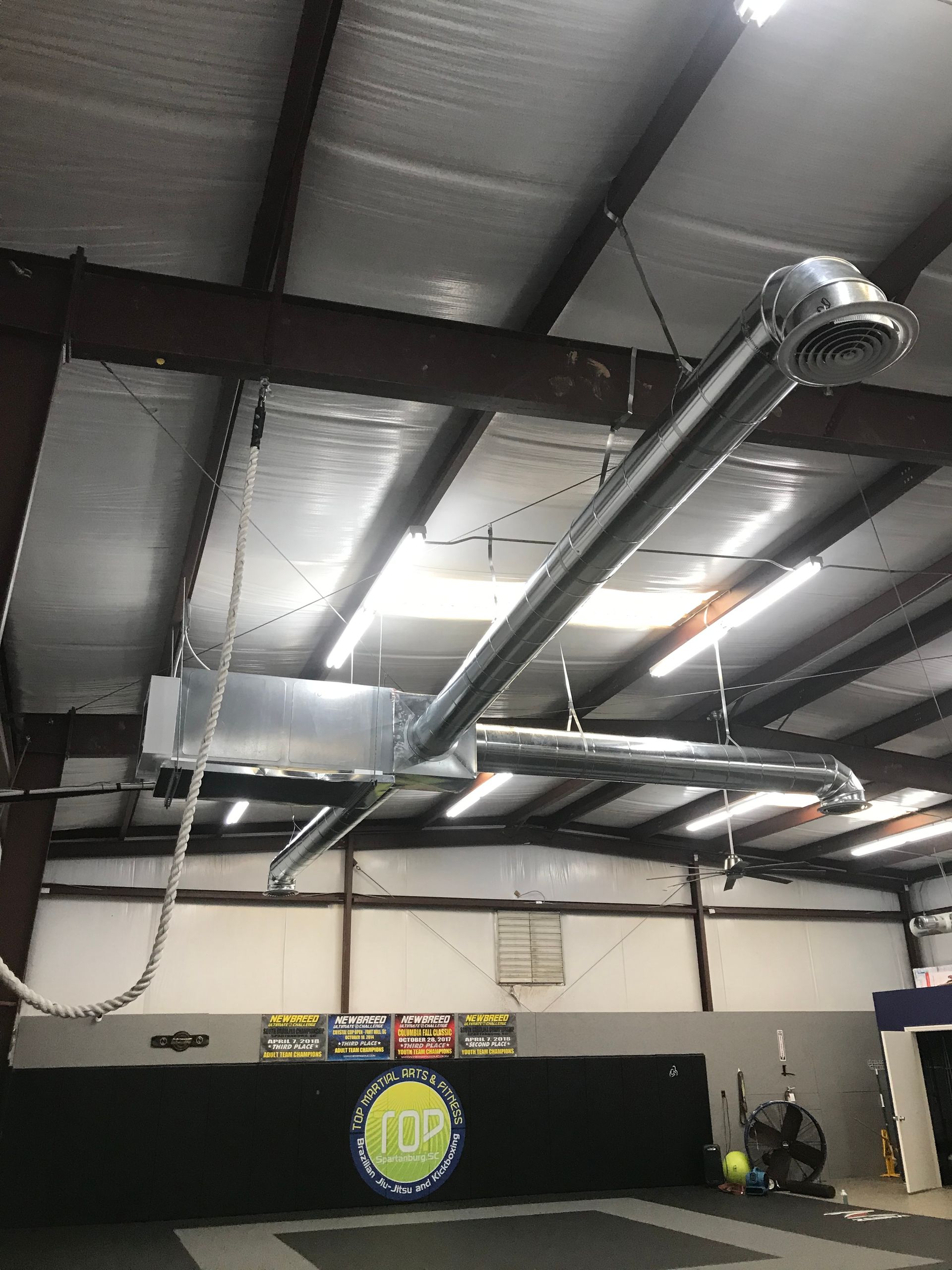 A large metal pipe is hanging from the ceiling of a gym.