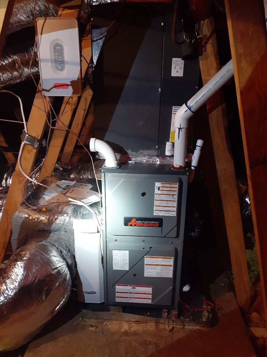 A furnace is sitting in the attic of a house.