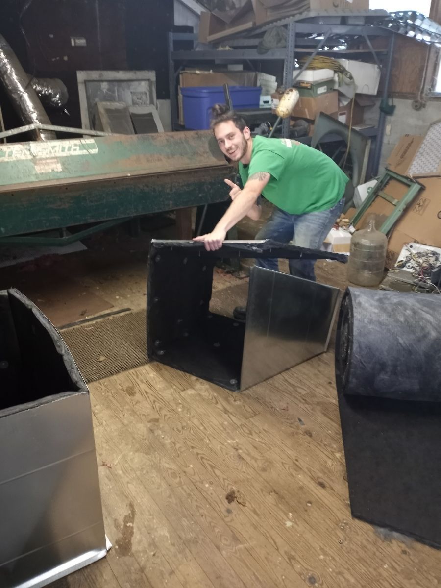 A man in a green shirt is holding a piece of metal