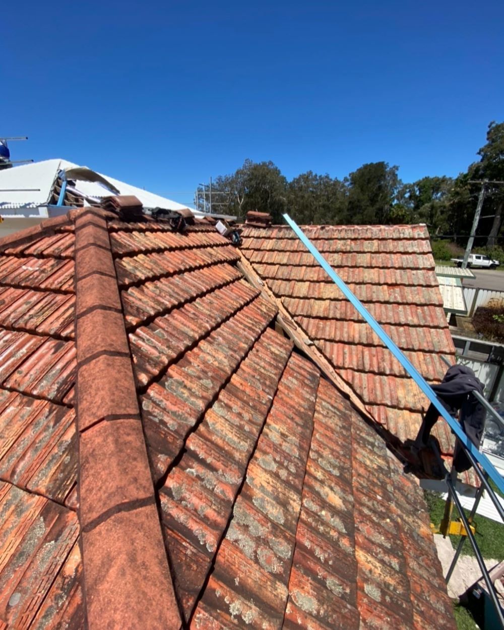 A Man is Working on the Roof of a House — Lake Valley Roofing in Aberglasslyn, NSW
