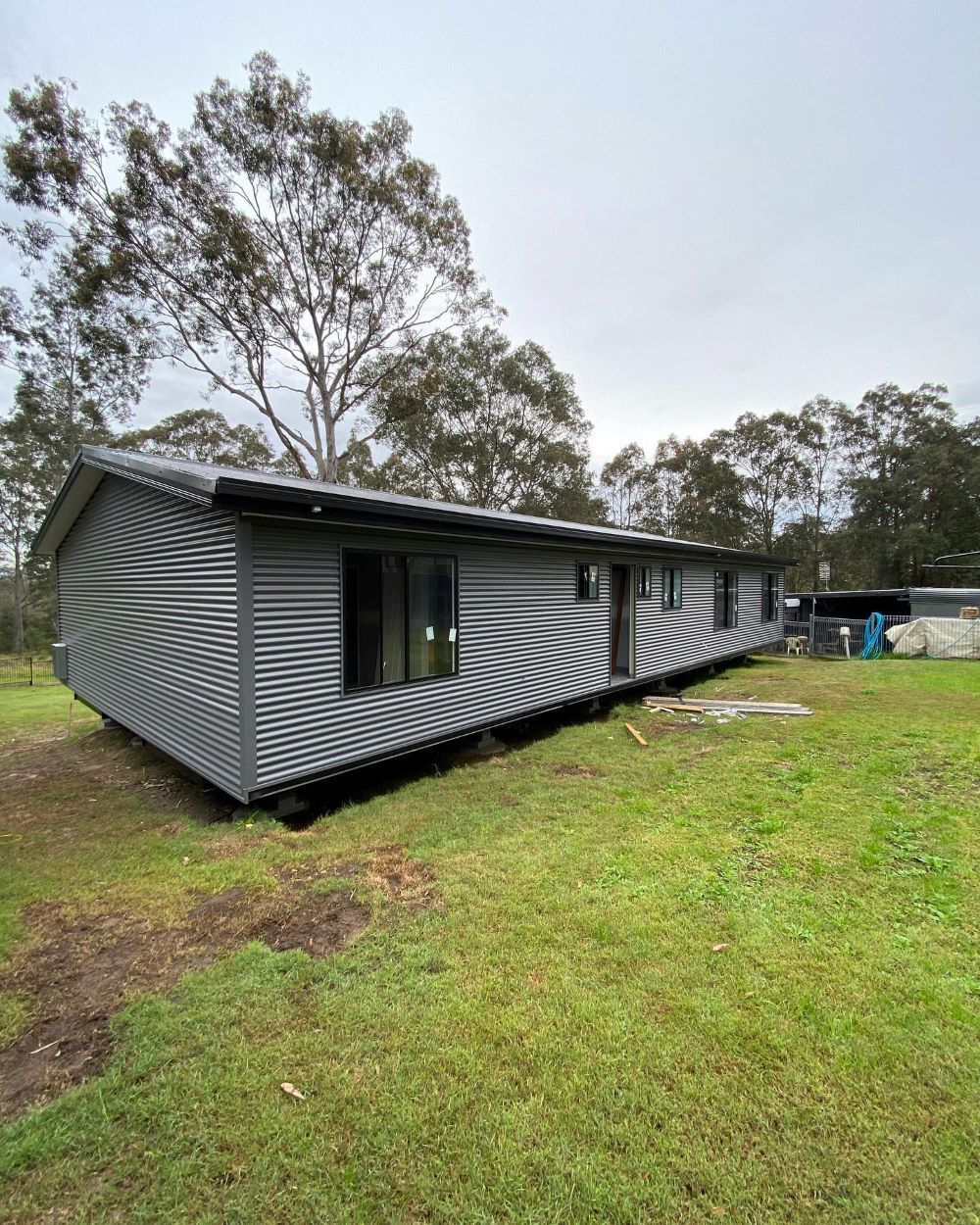 A Mobile Home is Sitting in the Middle of a Grassy Field — Lake Valley Roofing in Cardiff, NSW