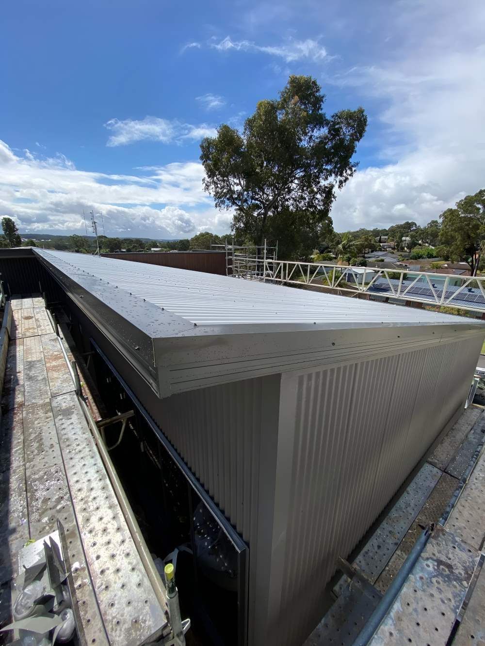 A Large Building With a Roof That is Being Built and a Tree in the Background — Lake Valley Roofing in Cooranbong, NSW