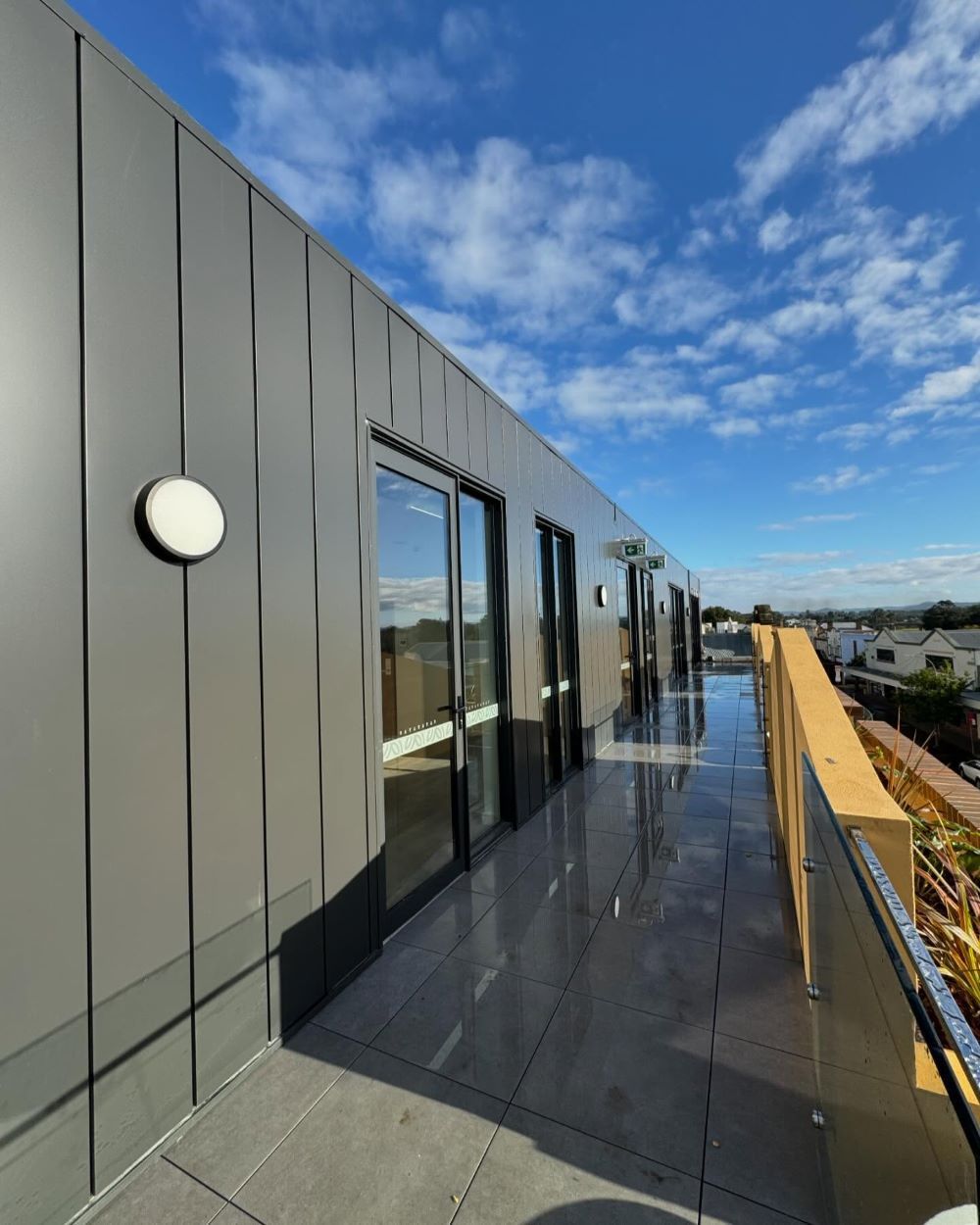 A Balcony on the Side of a Building With a Blue Sky in the Background — Lake Valley Roofing in Hamilton, NSW