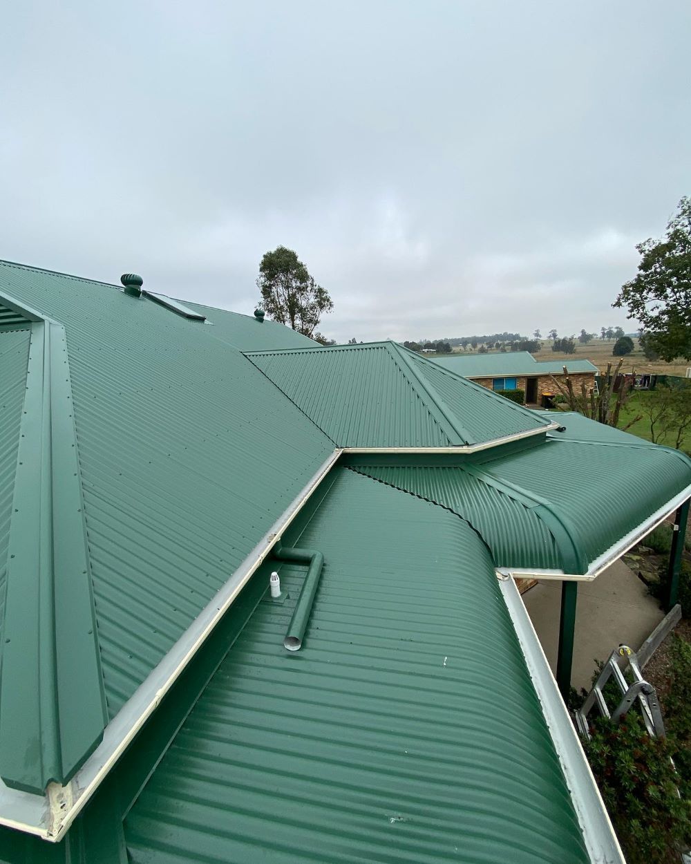 A Green Roof of a House With a White Trim on a Cloudy Day — Lake Valley Roofing in Kurri Kurri, NSW