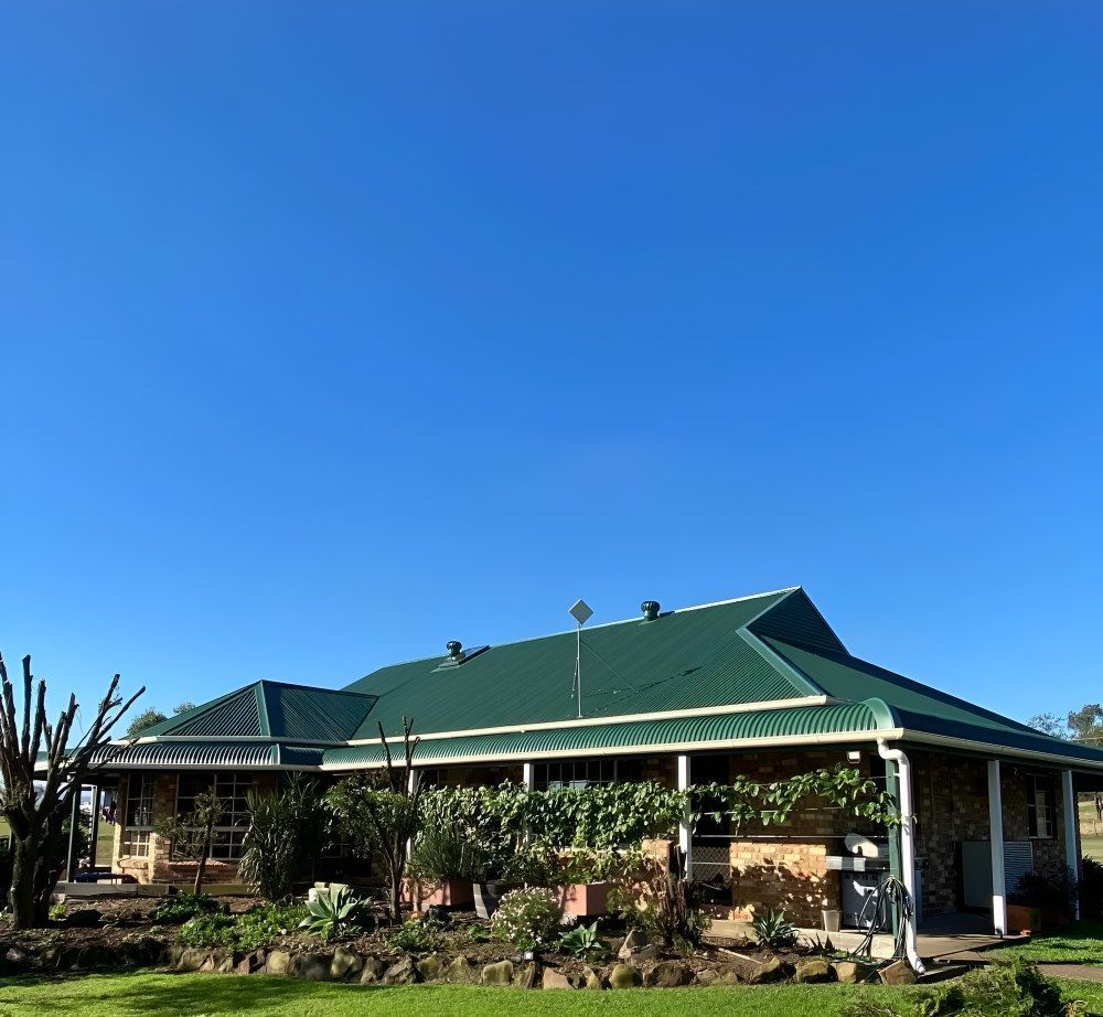A House With a Green Roof and a Blue Sky in the Background — Lake Valley Roofing in Cardiff, NSW