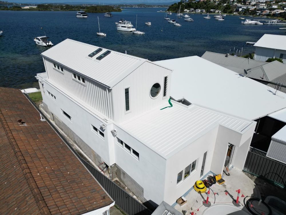 An Aerial View of a White House With Boats in the Background — Lake Valley Roofing in Tenambit, NSW