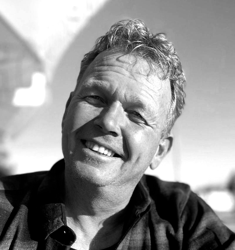 Smiling man, black and white, outdoors.