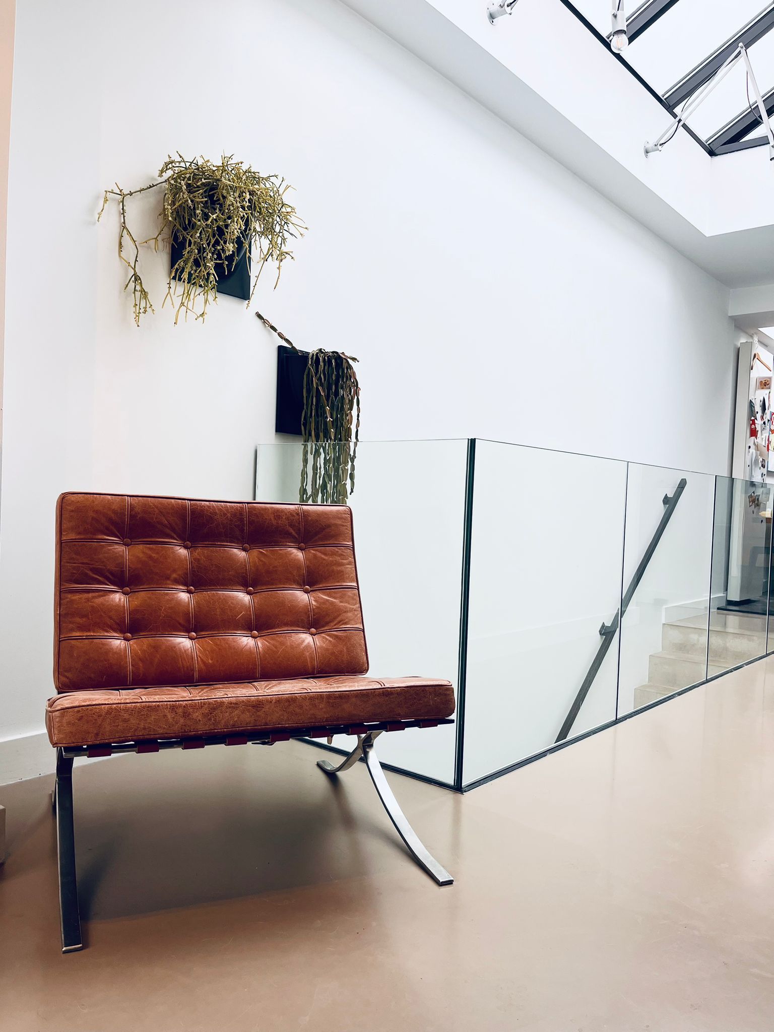 Brown leather chair, potted plants, and glass railing in a bright interior.