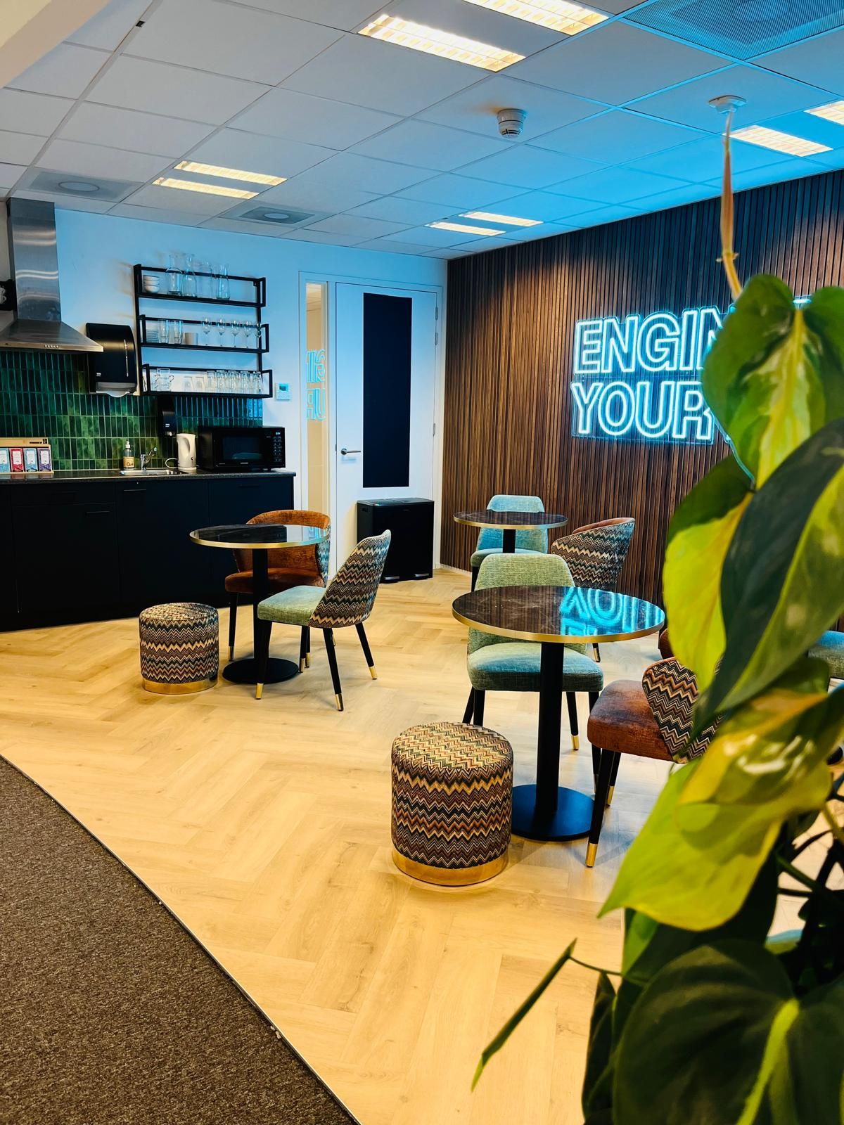 Cozy office breakroom with round tables, patterned chairs, and the words