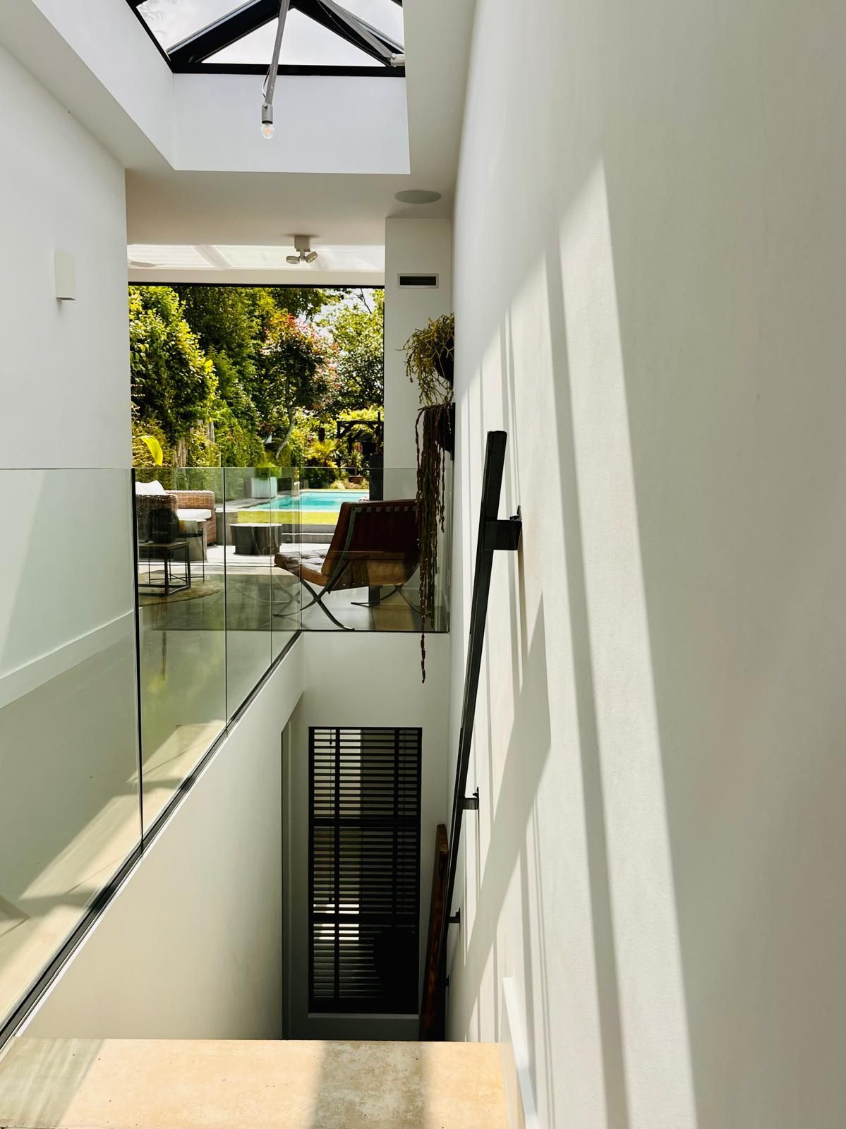 A descending staircase leads to a lower level with a view of a pool and lounge area.