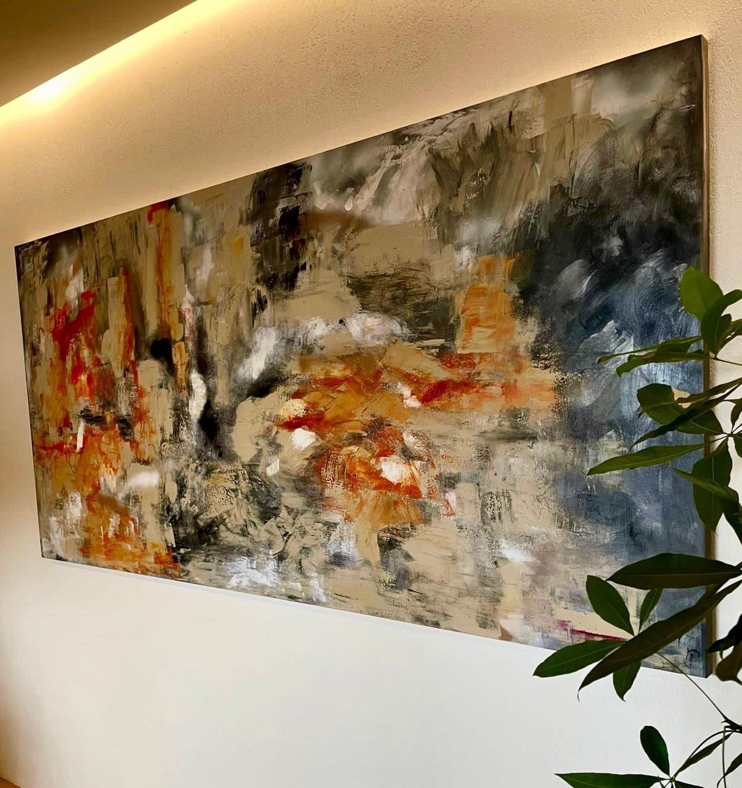 Abstract painting in neutral colors, with splashes of orange and red, mounted on a white wall.