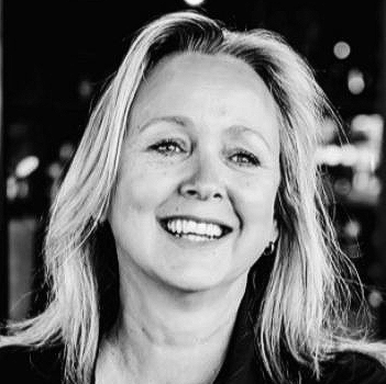 Smiling blond woman in black shirt.