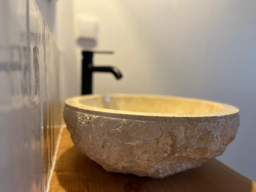 Stone vessel sink with black faucet in a bathroom.
